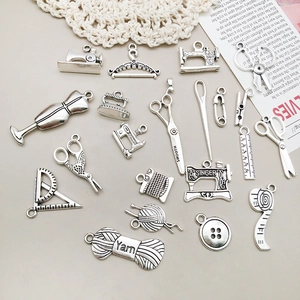 Vue détaillée des pendentifs de couture argentés vintage, ciseaux et machines à coudre