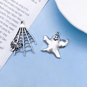 Gedetailleerde macro-opname van Halloween bedeltjes: spinnenweb en spook in vintage zilver