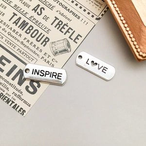 Makroaufnahme von Silberlegierungsanhängern mit INSPIRE- und LOVE-Gravur für DIY-Schmuck