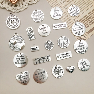 Dettagli di ciondoli vintage in argento con frasi ispiratrici per creazione di gioielli