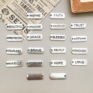 Detailansicht der silbernen Legierungsanhänger mit gravierten Worten wie INSPIRE und FAITH