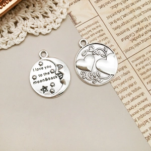 Dettaglio di ciondoli vintage in argento con motivi a cuore e incisione I love you to the moon