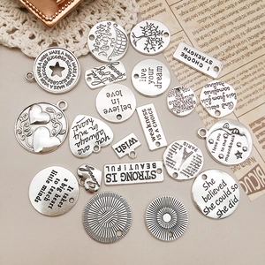 Dettaglio di ciondoli vintage in argento con citazioni ispiratrici e simboli incisi