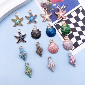 Macro shot of colorful enamel starfish and seashell charms with gold metal edges