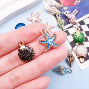 Detail of colorful alloy sea creature pendants held in hand for size reference