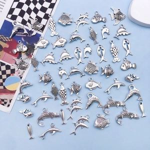 Close-up of vintage silver alloy charms featuring dolphins and tropical fish for DIY jewelry