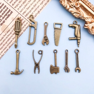 Vue macro de dix breloques outils miniatures en bronze vintage pour création de bijoux DIY