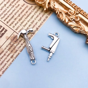 Détail de pendentifs marteau et perceuse en alliage argenté avec papier vintage sur bleu