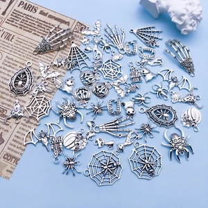 Flat lay of vintage silver Halloween charms including spiders and pumpkins for DIY jewelry
