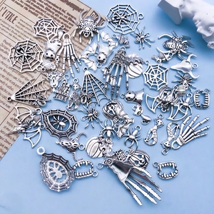 Flat lay of vintage silver Halloween charms including spiders and pumpkins for DIY jewelry