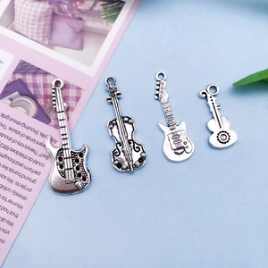 Close-up of four antique silver musical instrument charms including guitars and a violin