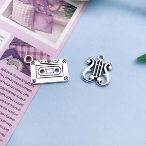 Close-up of vintage silver alloy charms featuring retro cassette tape and lyre harp designs
