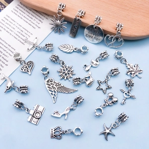 Detailed flat lay of diverse silver alloy DIY charms featuring hearts and angel wings