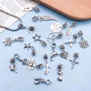 Macro detail of vintage silver alloy charms showing heart and wing motifs for DIY jewelry