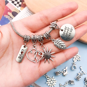 Vintage silver snake chain bracelet with five heart and sunflower charms on a wooden tray
