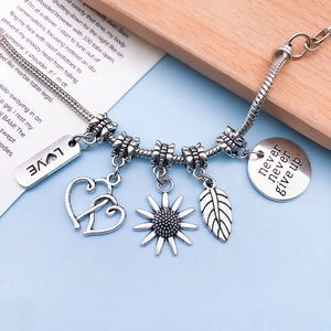 Detail view of retro silver snake chain bracelet with heart and leaf charms