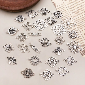 Vintage silver hollow flower alloy connectors for DIY jewelry making displayed on rustic paper