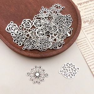 Macro detail of antique silver alloy flower charms with hollow mandala and tree patterns