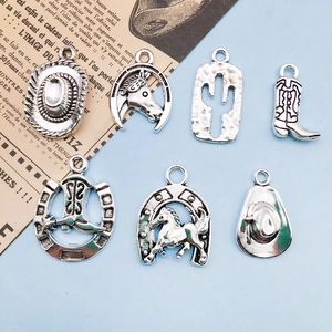 Detail of 7 vintage silver alloy cowboy charms including hat and boots on old newspaper