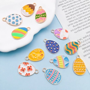 Flat lay of 12 colorful Easter egg charms with enamel bunny and floral patterns on alloy gold