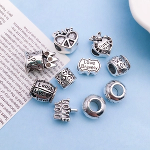 Close-up of vintage silver alloy charms featuring engraved love heart and peace motifs