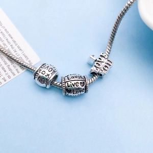 Detail view of vintage silver alloy beads with Love, Live, Laugh engraving on snake chain