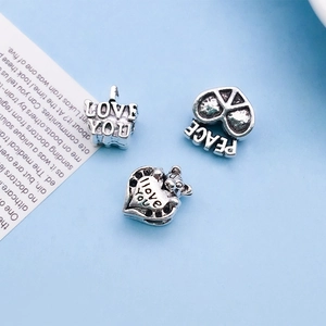 Detailed macro view of silver heart charms featuring LOVE YOU and PEACE engravings