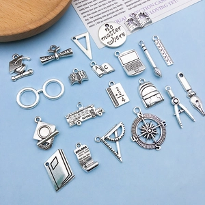Macro shot of silver graduation charms featuring graduation caps and school stationery items