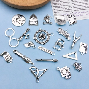 Detailed flat lay of silver graduation school stationery charms for DIY bracelets