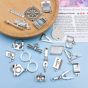 Detailed view of antique silver graduation charms including school bus and cap for DIY jewelry