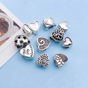 Detailed view of antique silver heart charms with engraved love text for DIY jewelry making