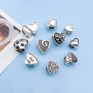 Detailed view of assorted antique silver heart charms with intricate engravings for DIY jewelry
