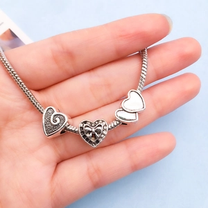 Detailed shot of silver heart charm bracelet featuring hollow and pavé crystal pendants
