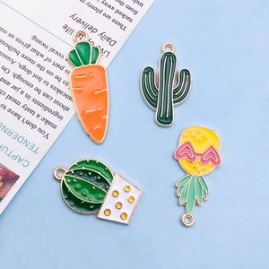 Flat lay of colorful enamel fruit and cactus pendants on a soft blue background