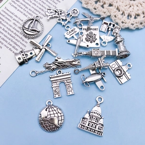 Macro view of vintage silver travel charms like Eiffel Tower and camera on blue background