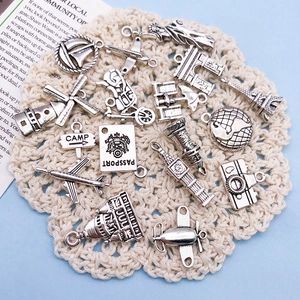 Detailed view of vintage silver alloy travel charms on white lace for DIY jewelry making