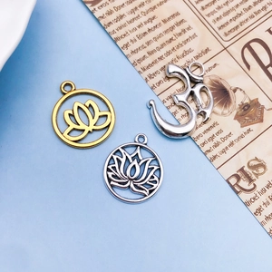 Detailed view of alloy lotus and Om charms for DIY necklaces on vintage background