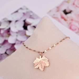 Elegant rose gold maple leaf pendant necklace with detailed veins on a velvet display stand