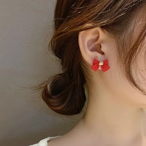 Elegantes pendientes de lazo rojo con detalle dorado en modelo para estilo dulce