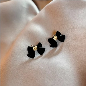 Elegantes pendientes de lazo de terciopelo negro con centro dorado sobre satén