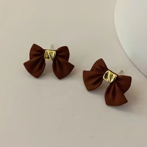 Detalle macro de pendientes de lazo de plata S925 con acabado marrón mate y toques dorados