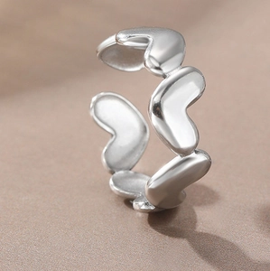 Vista detallada de un anillo de acero inoxidable plateado con diseño de corazones huecos