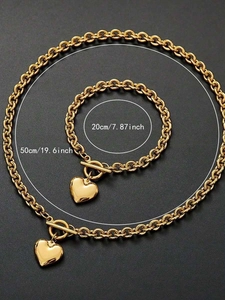 Vue détaillée de l'ensemble collier et bracelet en acier doré avec breloques cœur et fermoir OT
