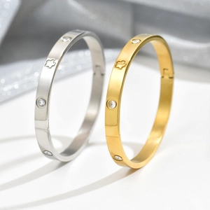 Detail van zilveren en gouden titanium stalen armbanden met klavermotieven en kristallen