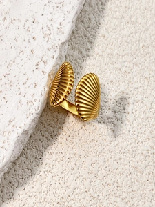 Detailed close-up of a golden seashell ring with fine radial textures on a stone surface