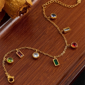 Bracelet doré en acier inoxydable orné de zircons colorés sur un plateau en bois