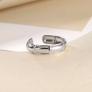 Detailed close-up of adjustable silver bamboo style ring on a minimalist pedestal
