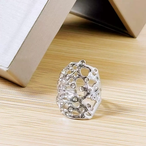 Detailed view of silver-tone hollow irregular textured ring on a wooden surface