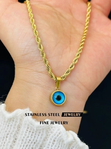 Close-up of stainless steel evil eye pendant with golden twisted rope chain detail