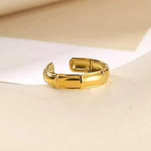Close-up of golden bamboo-joint style adjustable ring on minimalist geometric stand